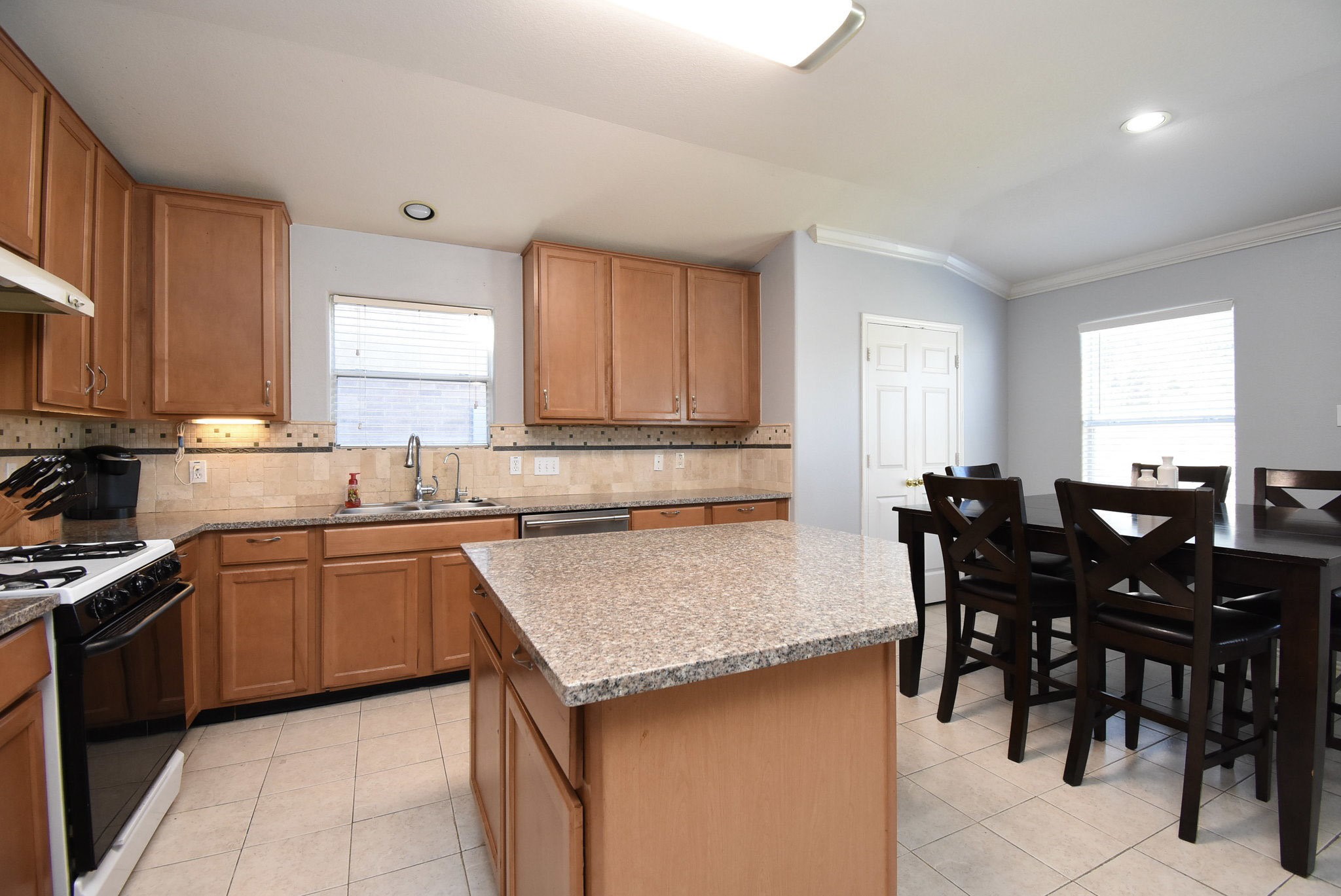 8502 Parapet Place Rosharon, TX 77583 - Photo 14 of 34 a kitchen with stainless steel appliances granite countertop wooden cabinets a dining table and chairs
