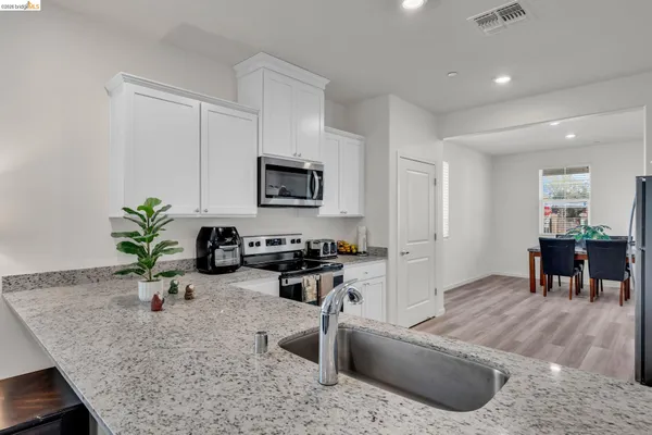 a kitchen with stainless steel appliances granite countertop a stove a sink and a microwave