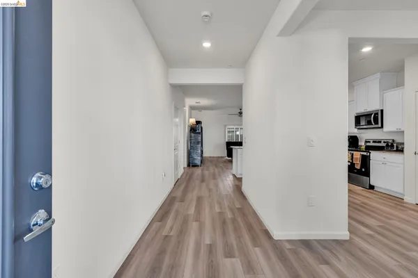 a view of a hallway with wooden floor and a kitchen space