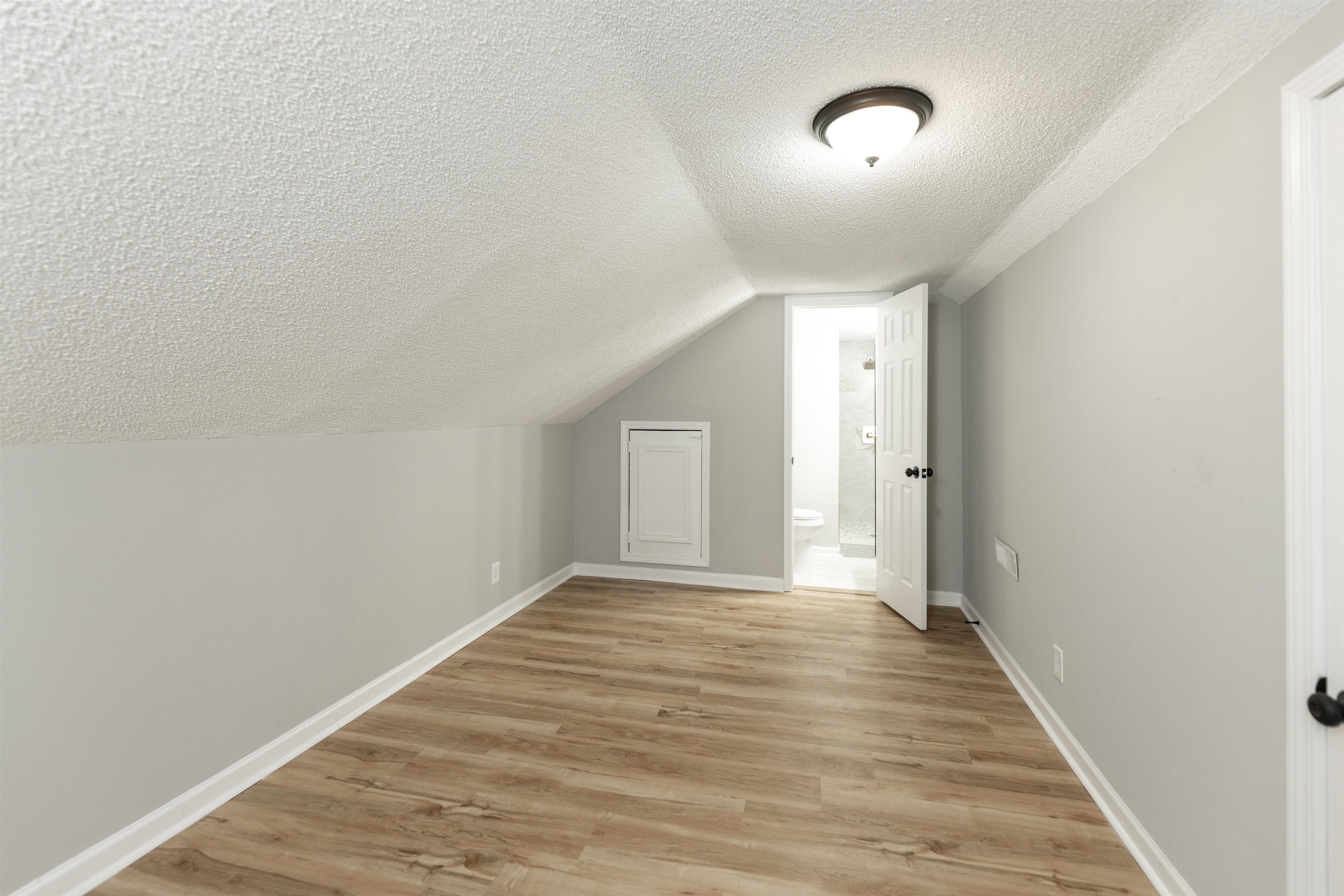 7421 Richmond Road Memphis, TN 38125 - Photo 33 of 39 Attic room with wood-finish flooring, light gray walls, and a sloped ceiling