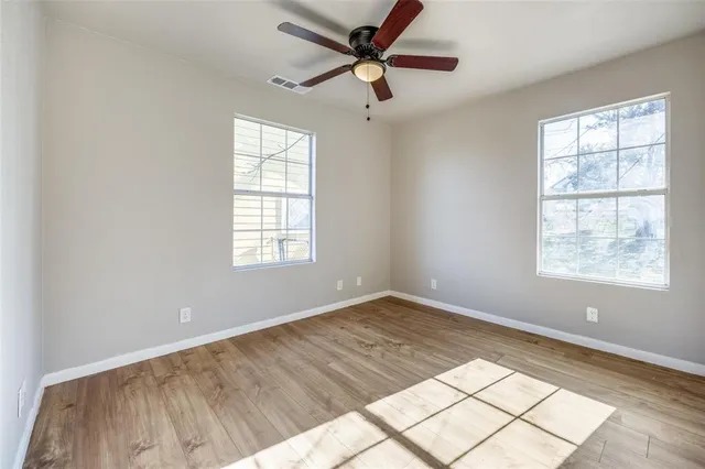 an empty room with windows and fan