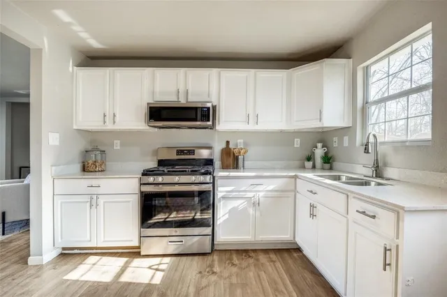 a kitchen with cabinets stainless steel appliances a sink and a window
