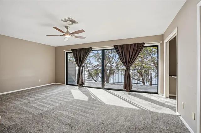 an empty room with large windows and a ceiling fan
