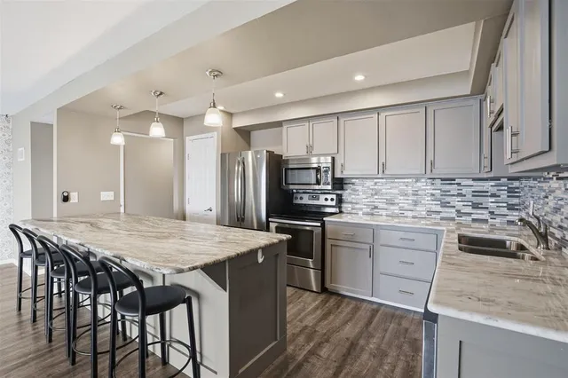a kitchen with stainless steel appliances kitchen island granite countertop a kitchen island and chairs in it
