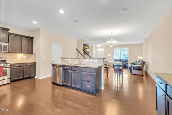 a kitchen with stainless steel appliances granite countertop a stove a sink a refrigerator and chairs