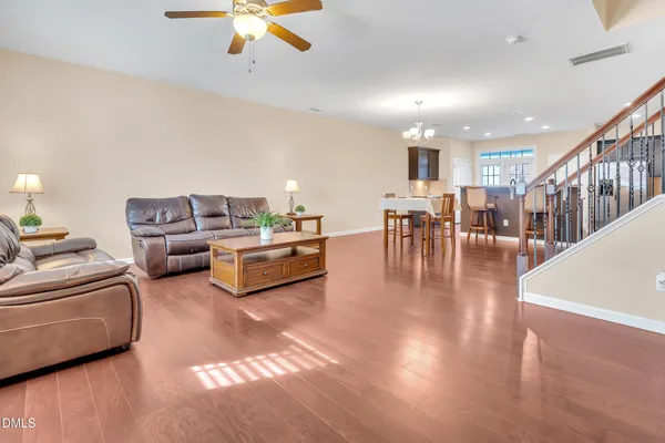 a living room with furniture and a dining table with wooden floor