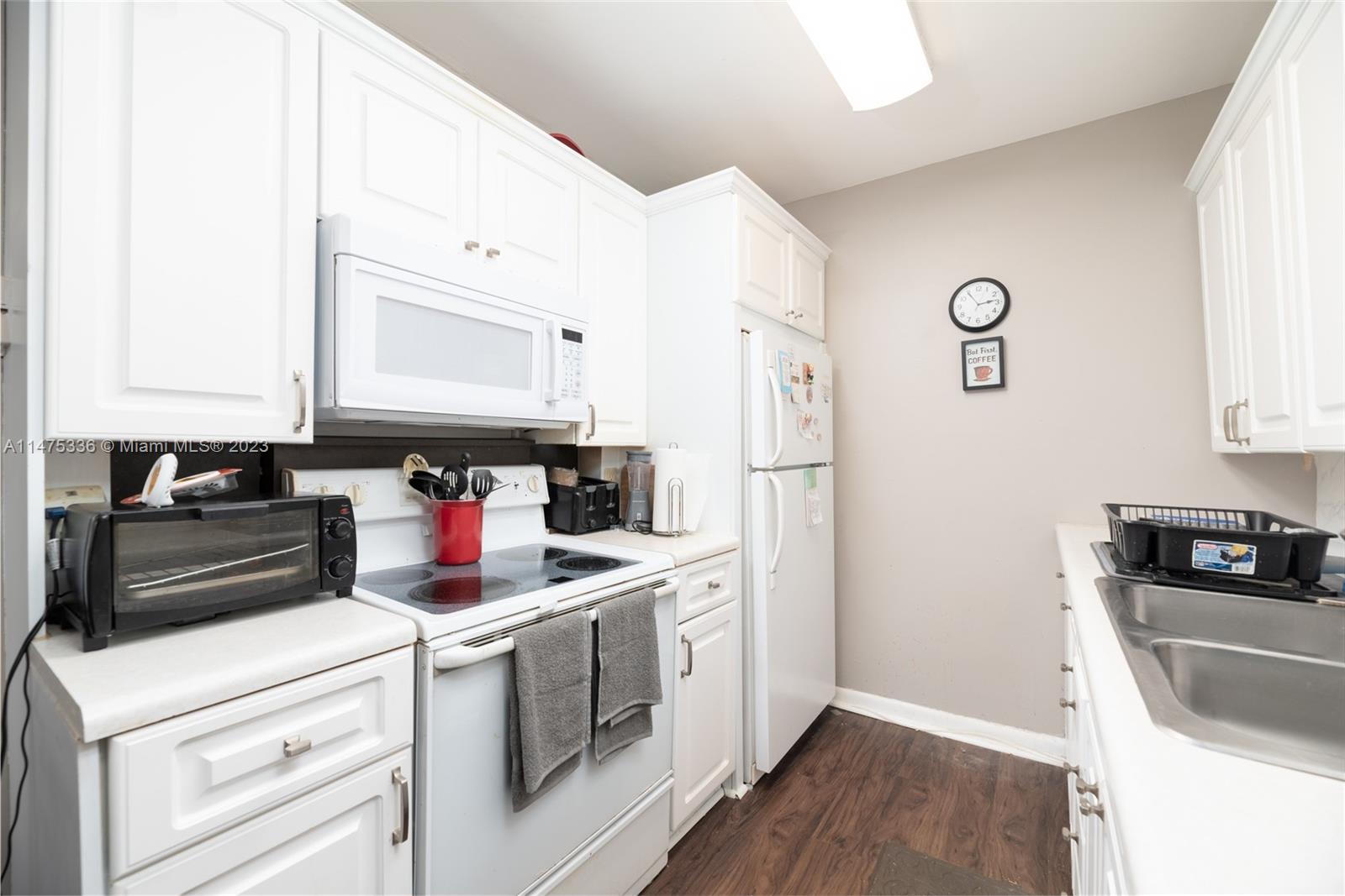 2085 Exeter, Unit 2085 Boca Raton, FL 33434 - Photo 8 of 20 a kitchen with a refrigerator stove and white cabinets