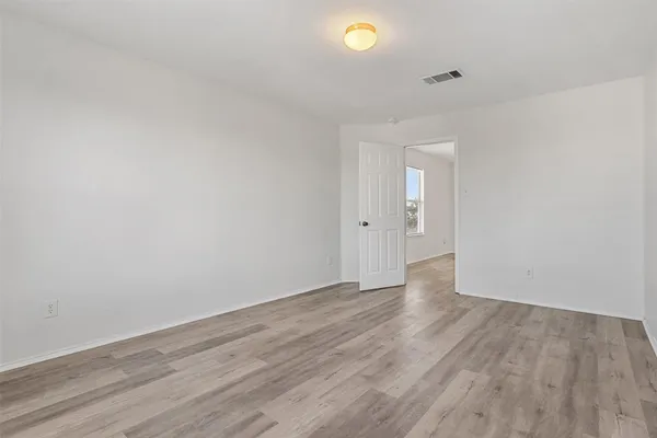 an empty room with wooden floor and mirror