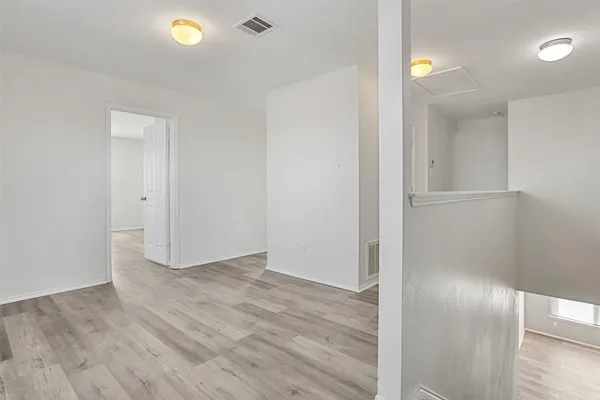 an empty room with wooden floor and mirror