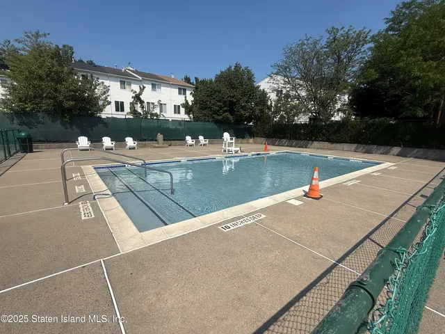 a view of swimming pool with outdoor seating and trees in the background