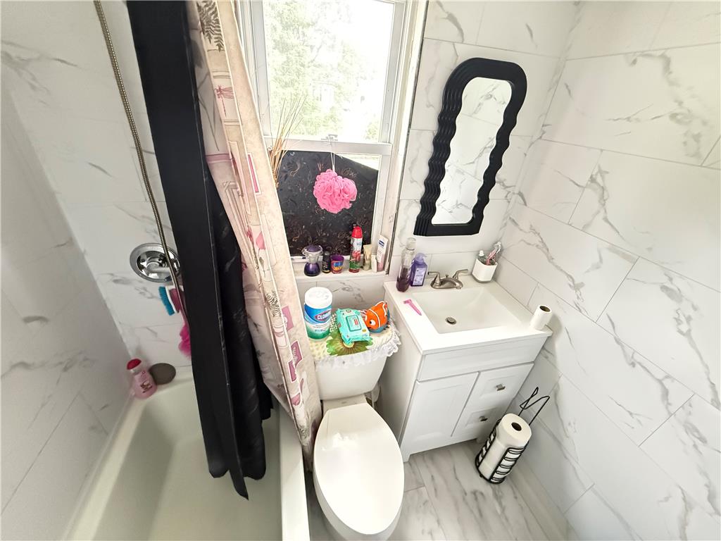 700 Philo Street Scranton, PA 18508 - Photo 13 of 19 A compact bathroom featuring sleek tiled walls and flooring, complemented by a modern vanity.
