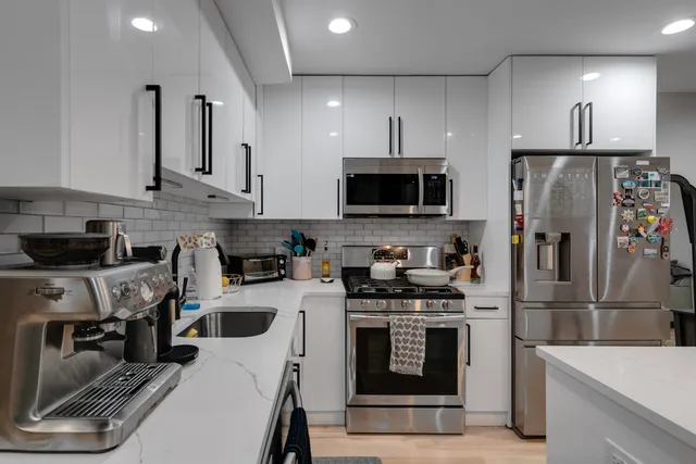 a kitchen with stainless steel appliances a stove a sink a refrigerator a microwave and cabinets