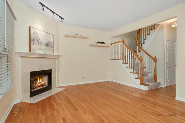 a view of an empty room with wooden floor fireplace and a window