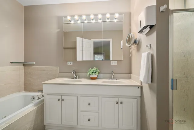 a bathroom with a sink double vanity granite tub shower and a mirror