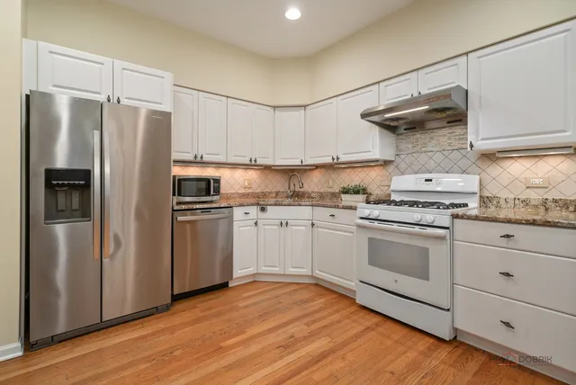 a kitchen with white cabinets and stainless steel appliances