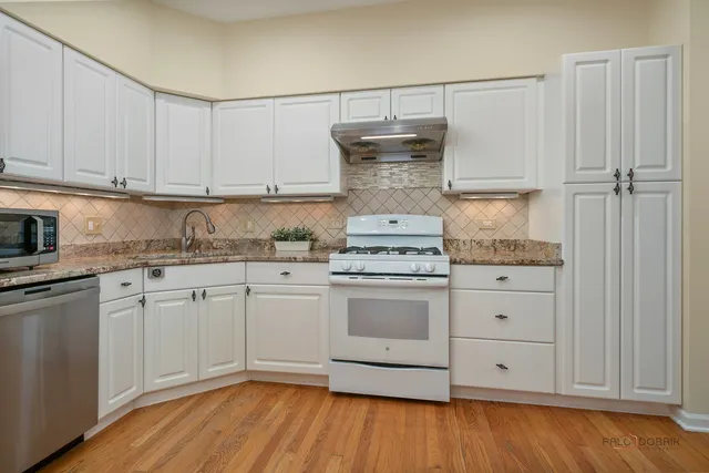 a kitchen with granite countertop white cabinets and white appliances