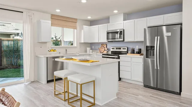 a kitchen with stainless steel appliances a refrigerator a stove a sink cabinets and wooden floor