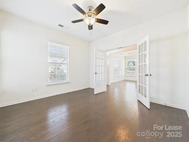 a view of an empty room with window and wooden floor