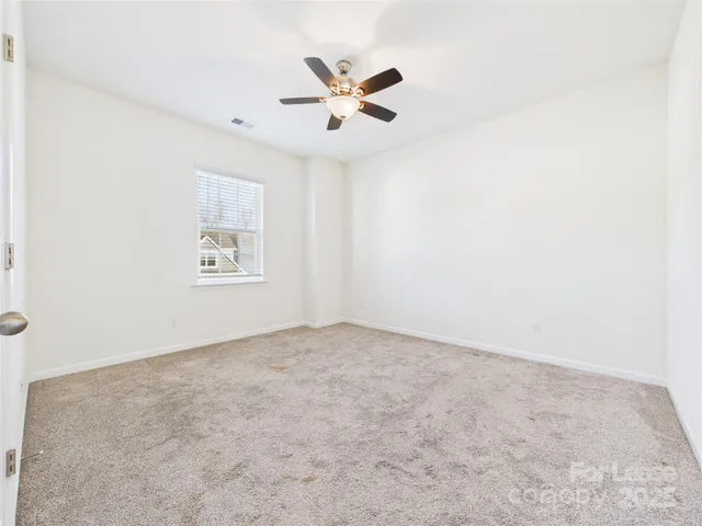 an empty room with closet and ceiling fan