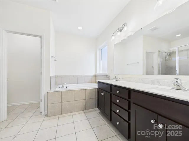 a spacious bathroom with a double vanity sink a mirror and a bathtub