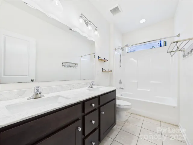 a bathroom with a tub sink double vanity and shower
