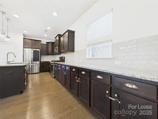 a large kitchen with stainless steel appliances kitchen island granite countertop a sink and cabinets