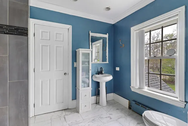 a bathroom with a sink toilet a mirror and window