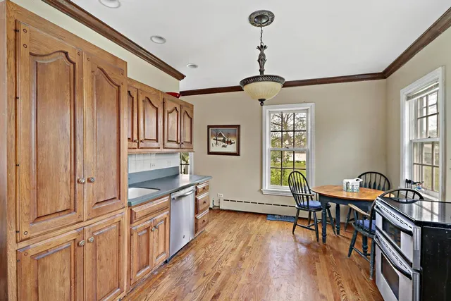 a kitchen with stainless steel appliances granite countertop a stove top oven a dining table and chairs with wooden floor