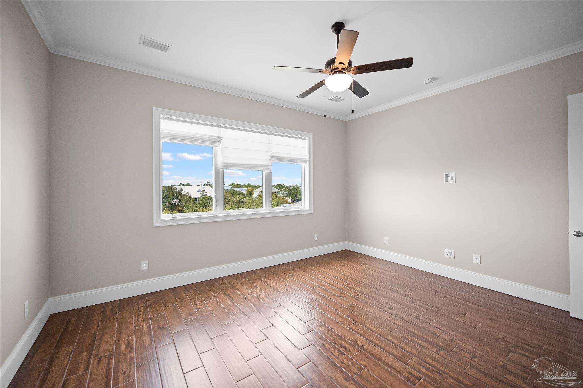 31729 River Road Orange Beach, AL 36561 - Photo 16 of 57 an empty room with wooden floor ceiling fan and windows