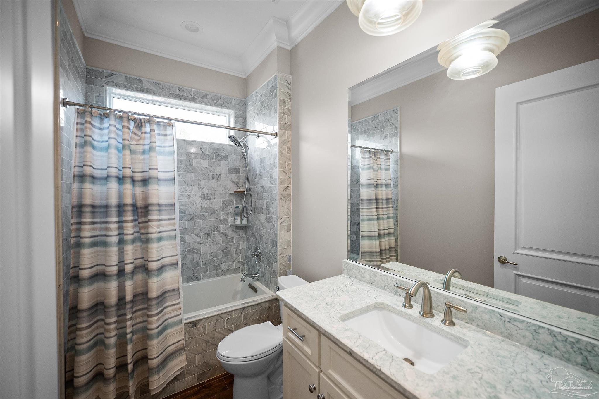 31729 River Road Orange Beach, AL 36561 - Photo 23 of 57 a bathroom with a granite countertop sink a toilet a mirror a bathtub and shower