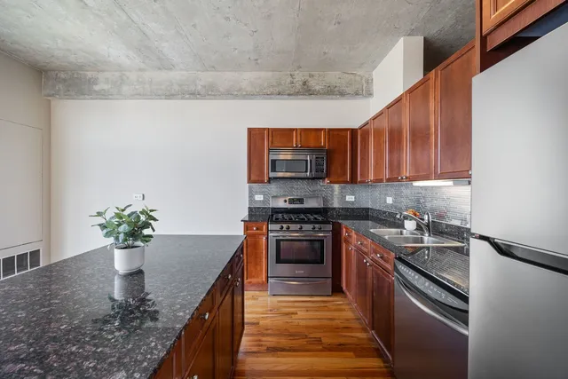 a kitchen with stainless steel appliances granite countertop a sink a stove top oven a counter space and cabinets