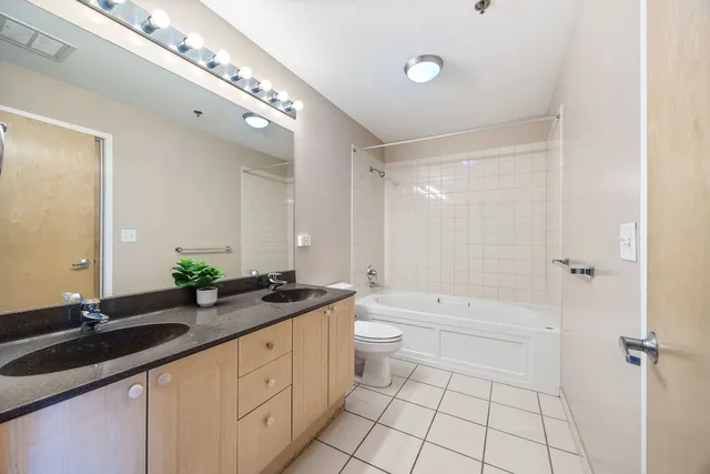 a spacious bathroom with a granite countertop sink a toilet a mirror and shower