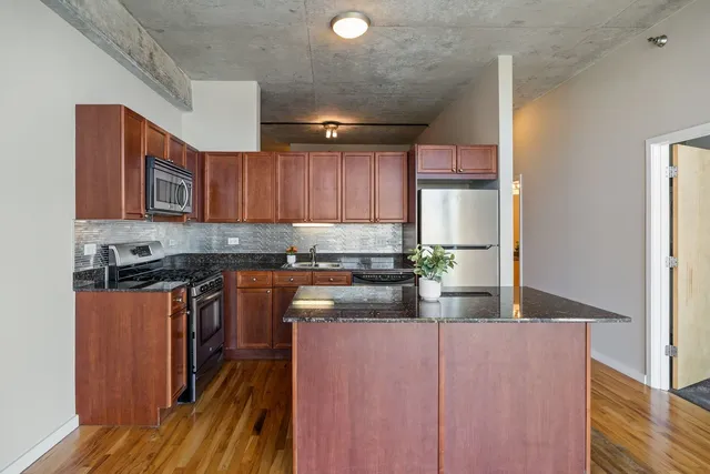 a kitchen with stainless steel appliances granite countertop wooden cabinets a stove top oven a sink and dishwasher
