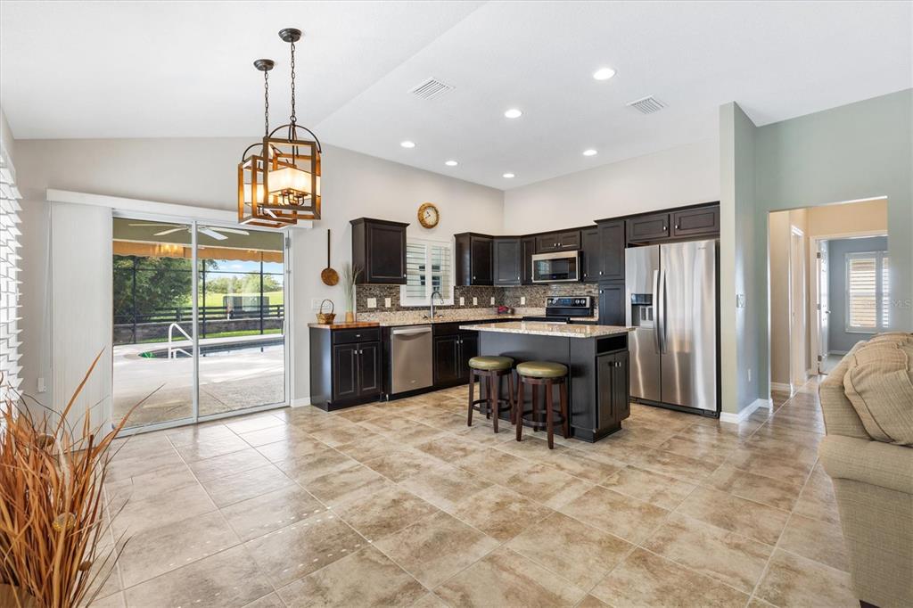 7351 Southeast 169th Cote Loop The Villages, FL 32162 - Photo 9 of 32 a kitchen with kitchen island a refrigerator a stove a sink and a dining table with wooden floor