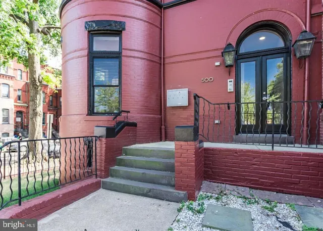 a view of a brick house with a large windows and a flower plants with wooden fence