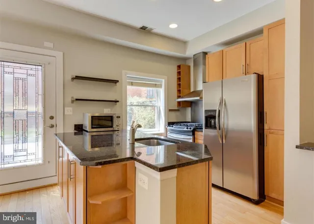 a kitchen with a refrigerator a stove a sink dishwasher and wooden cabinets with wooden floor