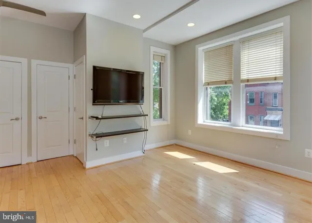 a view of an empty room with a window and a kitchen