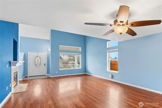 a view of an empty room with window and wooden floor