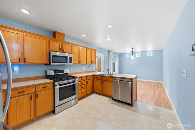 a kitchen with stainless steel appliances granite countertop a stove a sink and a microwave