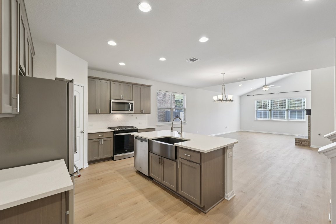 308 Castlefields Street Hutto, TX 78634 - Photo 11 of 31 a kitchen with stainless steel appliances granite countertop a stove top oven a sink a refrigerator and white cabinets