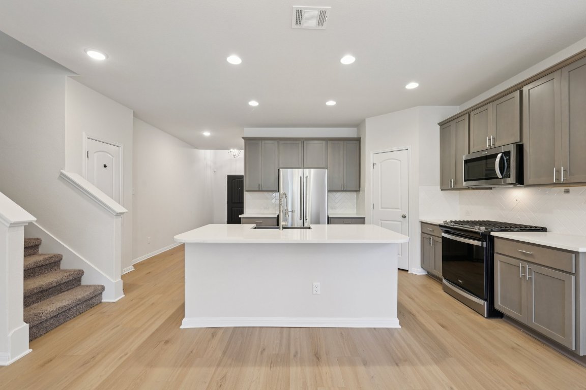 308 Castlefields Street Hutto, TX 78634 - Photo 2 of 31 a large kitchen with stainless steel appliances granite countertop a stove and a sink