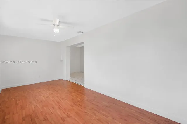 an empty room with wooden floor and fan
