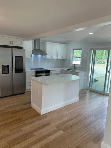 a large kitchen with stainless steel appliances granite countertop a stove a sink and a refrigerator