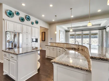 a kitchen with stainless steel appliances granite countertop a sink and a refrigerator
