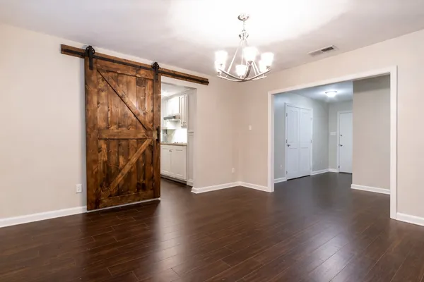 an empty room with wooden floor chandelier and windows