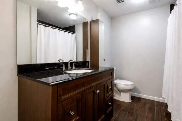 a bathroom with a granite countertop sink toilet and mirror