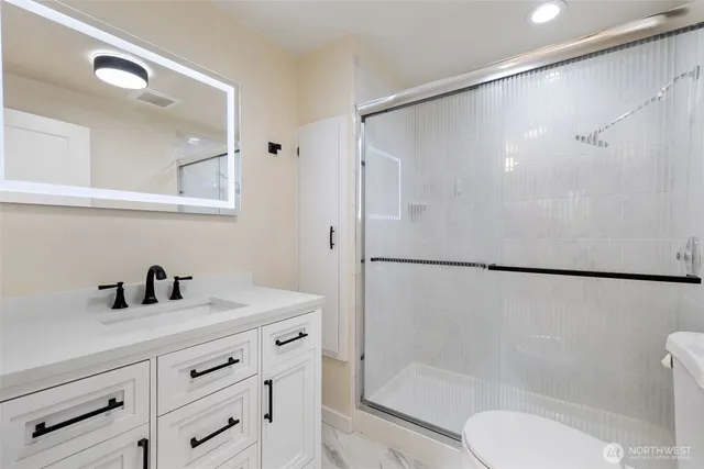 a bathroom with a shower sink vanity mirror and toilet