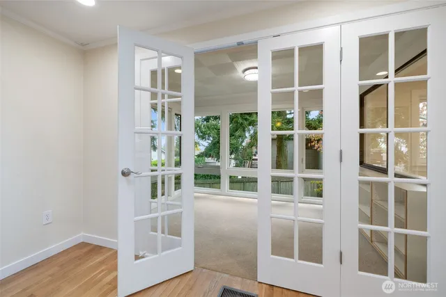 a view of an empty room with wooden floor and windows
