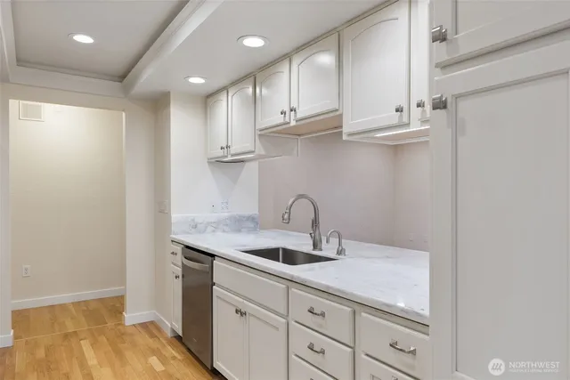 a kitchen with white cabinets a sink and dishwasher