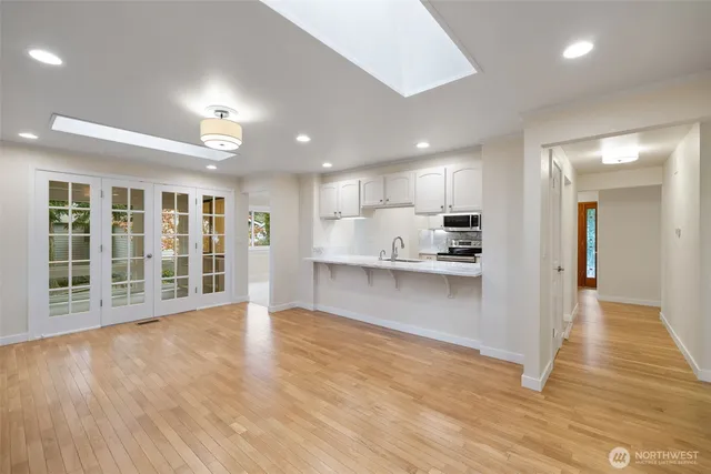 a view of an empty room with kitchen and window